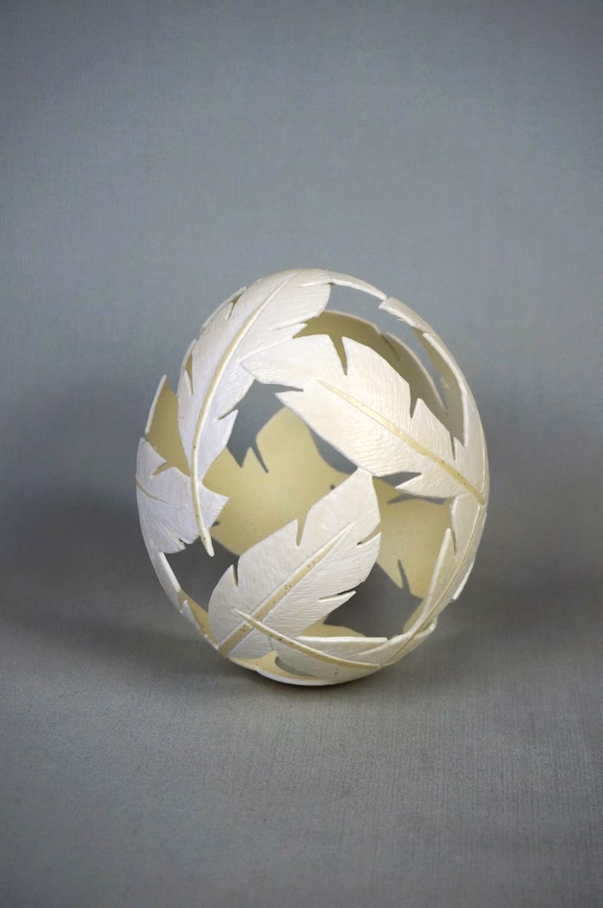 Auf dem Bild wird die StraußenEi-Skulptur " FederLeicht " gezeigt. Mehre Federn sin ineinander verwoben. Das StraußenEi wurde graviert und gefräst. Diese Skulptur wurde für den Erna-Suhrborg-Preis-2026 juriert und steht in der Ausstellung im Städtischen Bühnenhaus der Stadt Wesel vom 18.01. bis 8.03.2026.